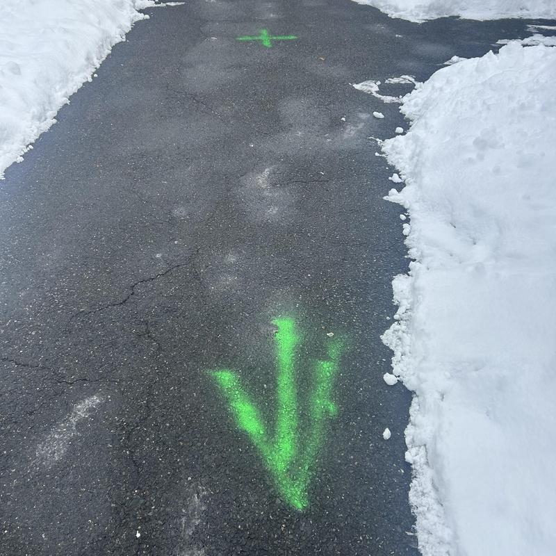 Main line sewer markings on snowy residential driveway