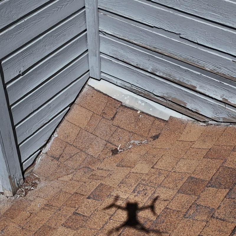 Asphalt shingle roof corner with wood siding damage Asphalt shingle roof corner with wood siding damage