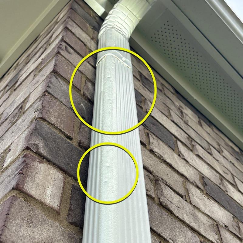 Downspout dents and damage on brick exterior wall