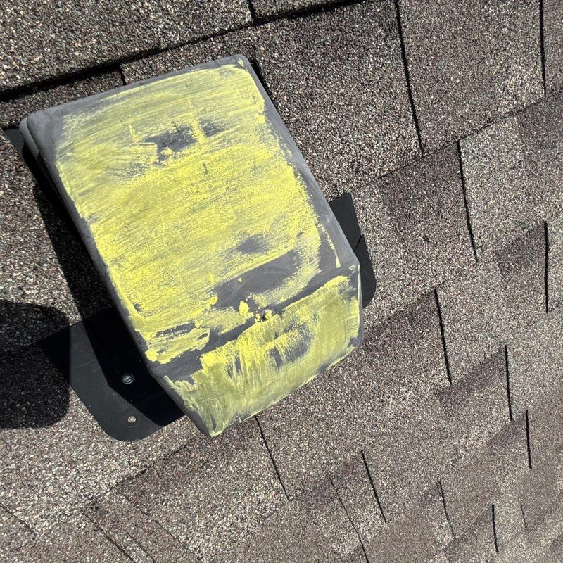 Roof vent with yellow chalk marking on asphalt shingles