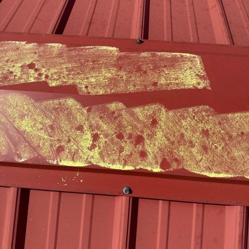 Metal roof ridge cap with hail damage marked in yellow