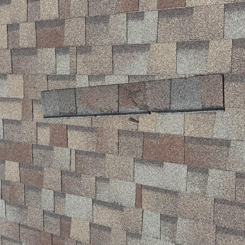 Asphalt shingle roof with damaged and missing shingles