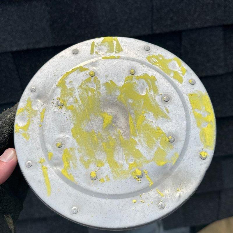 Metal roof vent cap with hail damage and yellow markings