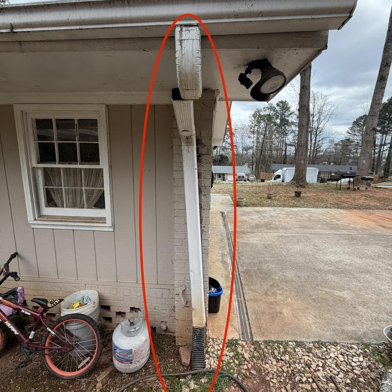 Downspout re-fastened to brick exterior wall