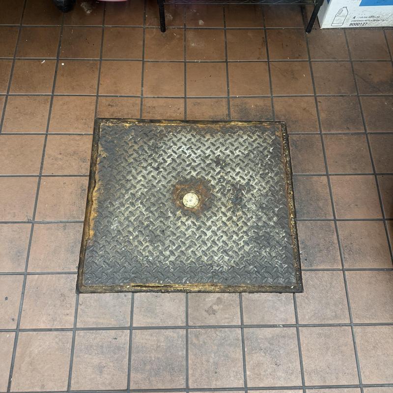 Metal floor access panel on tiled floor