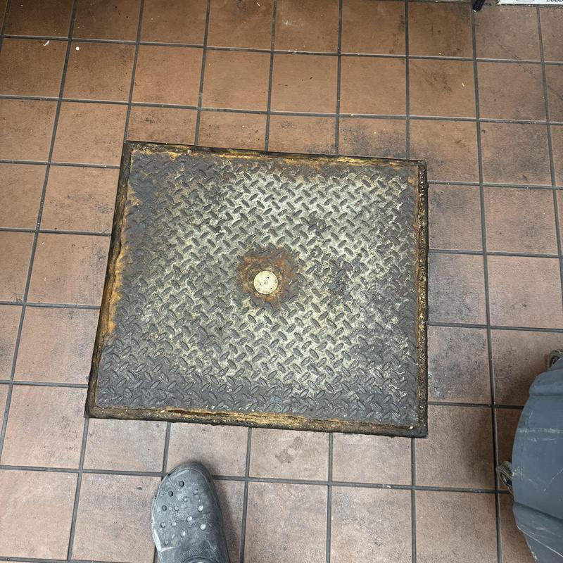 Floor drain cover in tiled commercial restroom floor
