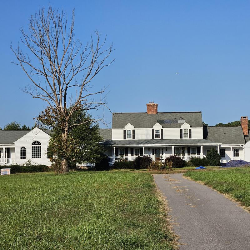Farmhouse roof replacement with gutters and driveway