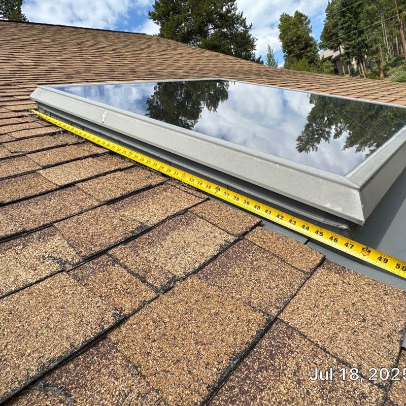 Skylight on asphalt shingle roof with measuring tape Skylight on asphalt shingle roof with measuring tape