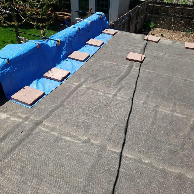 Flat roof with blue tarp and concrete blocks weighing edges Flat roof with blue tarp and concrete blocks weighing edges