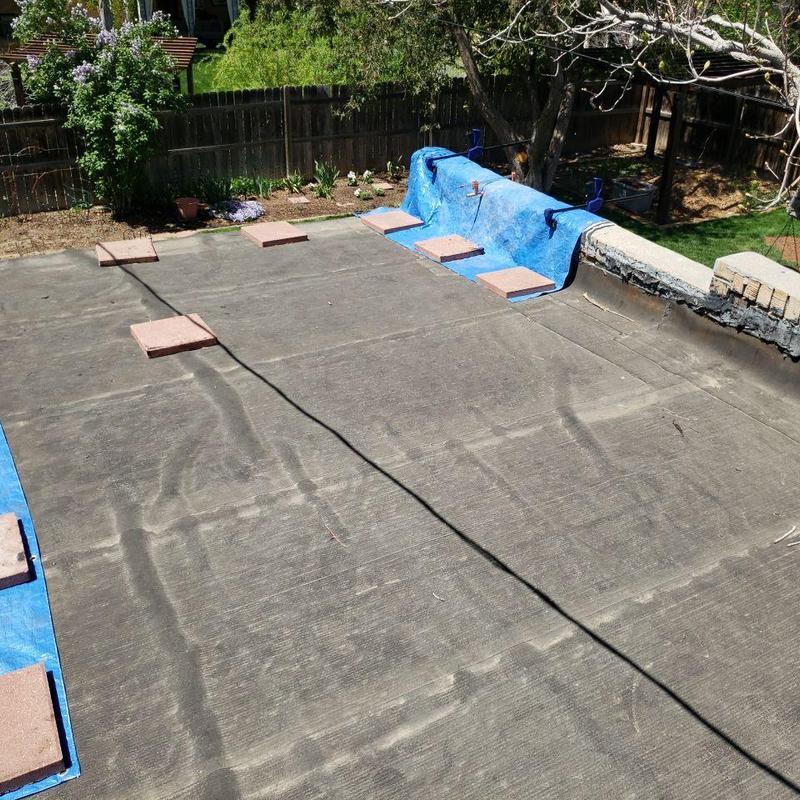 Flat roof with tarp and weighted bricks in backyard Flat roof with tarp and weighted bricks in backyard