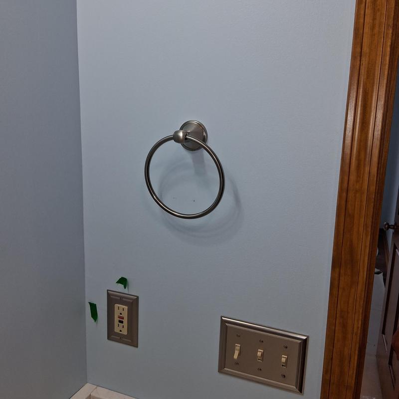 Bathroom towel ring installation on blue wall next to switches