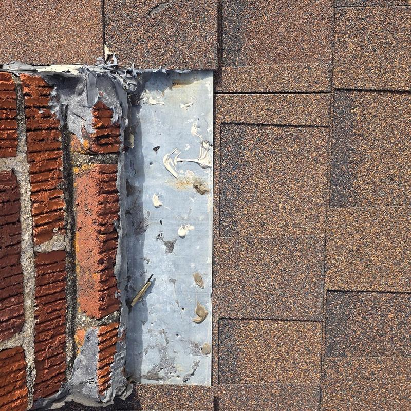 Roof flashing with hail damage near brick chimney