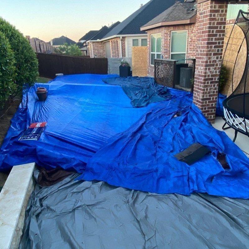 Roof under protective blue tarp covering landscaping and pool equipment Roof under protective blue tarp covering landscaping and pool equipment