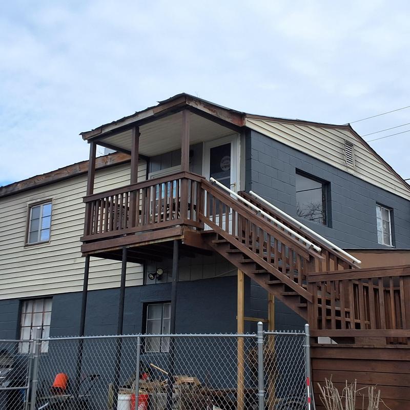 Metal roof inspection on converted garage with deck stairs