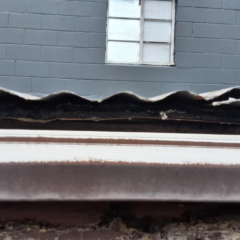 Old metal roof edge with rust and damage gap