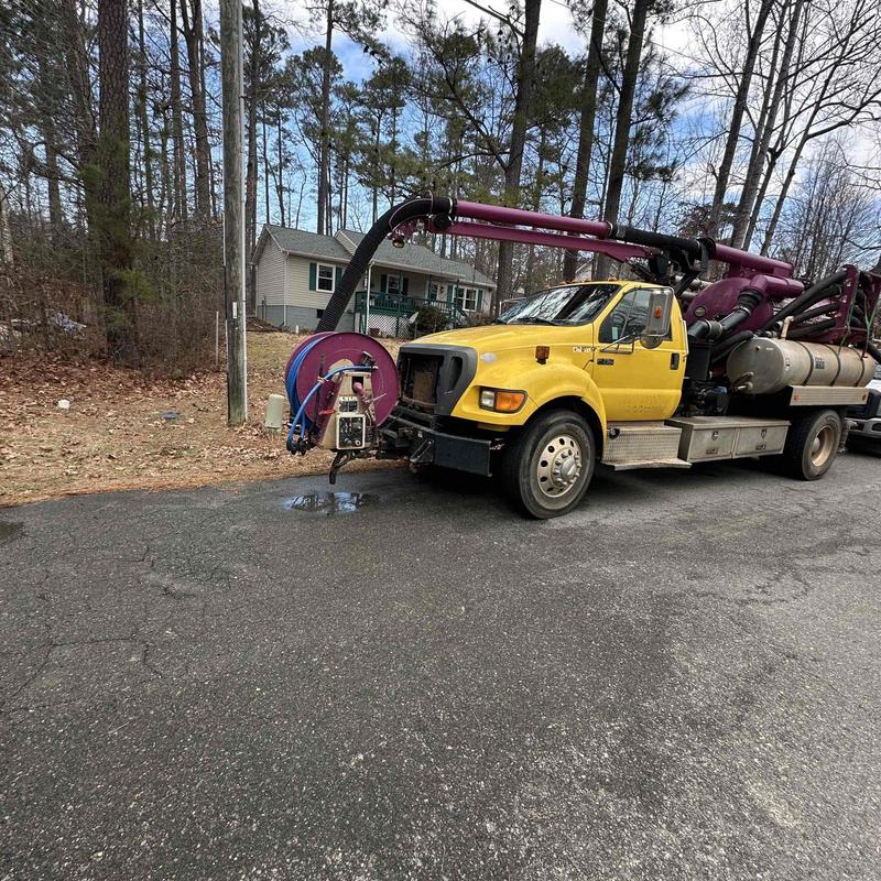 Vacuum truck with hose reel parked by roadside Vacuum truck with hose reel parked by roadside