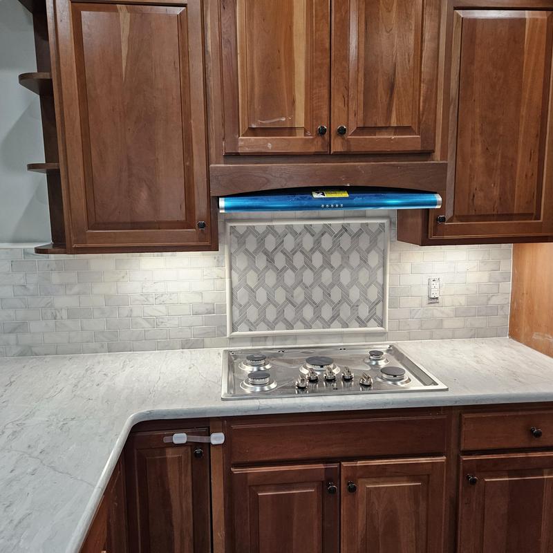 Gas cooktop with decorative tile backsplash and wooden cabinets Gas cooktop with decorative tile backsplash and wooden cabinets