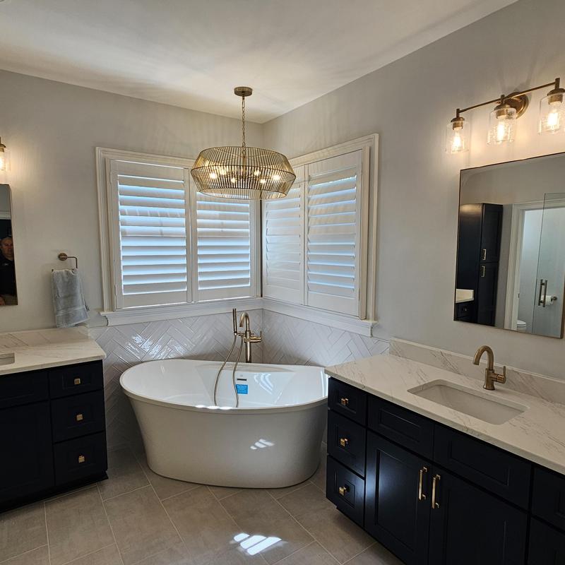 Freestanding bathtub with gold fixtures and dark cabinets Freestanding bathtub with gold fixtures and dark cabinets