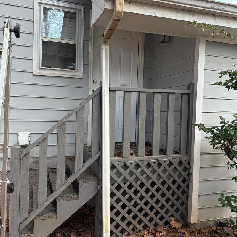 Downspout reattached to house exterior near porch steps