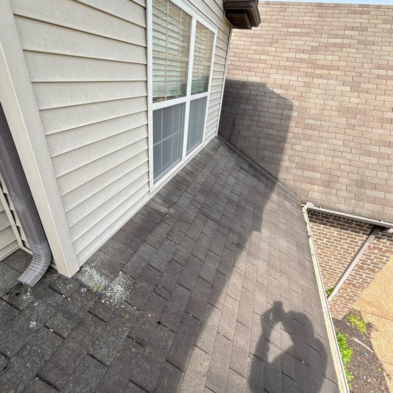 Asphalt shingle roof with hail damage near window wall