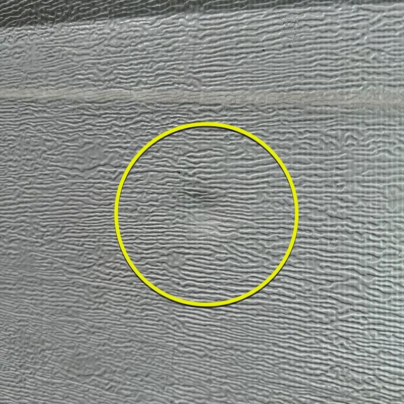Asphalt shingle hail damage close-up with yellow circle