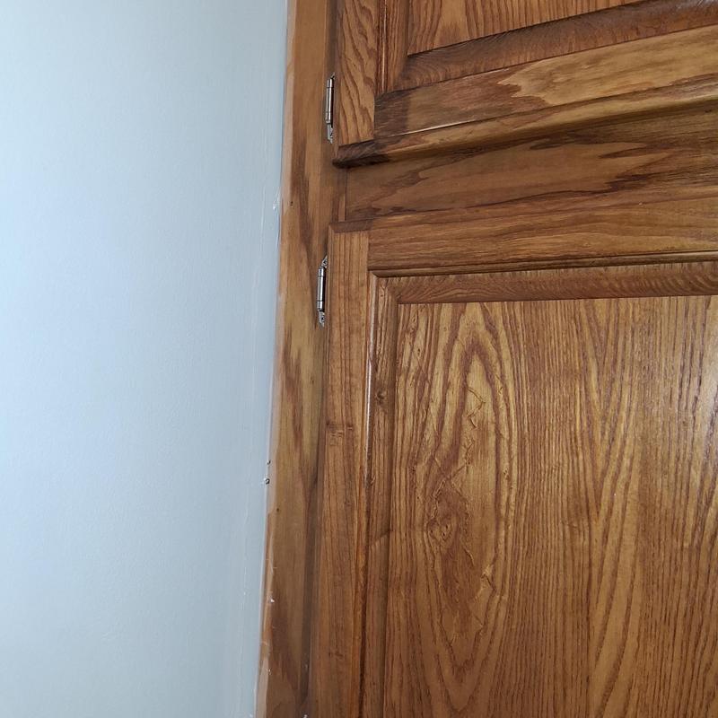 Wood door trim with patch and stain near wall