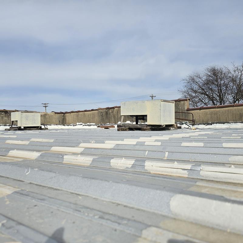Metal roof with hail damage near rooftop HVAC units
