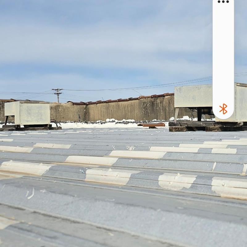 Metal roof panels with hail damage and rooftop units