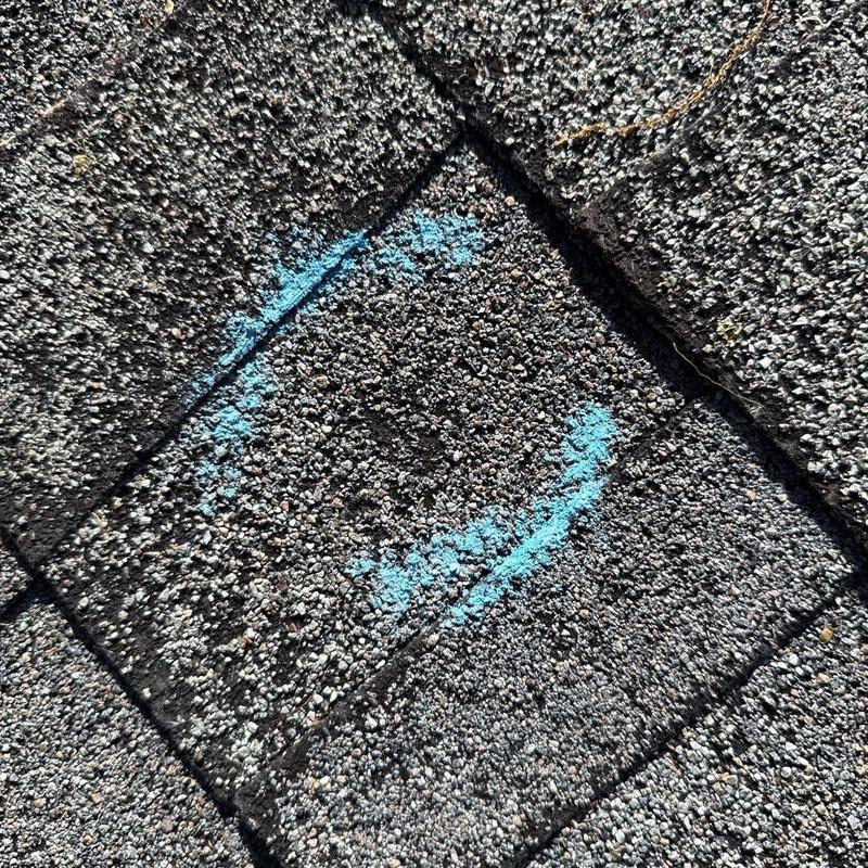 Asphalt shingle with marked hail damage on roof surface