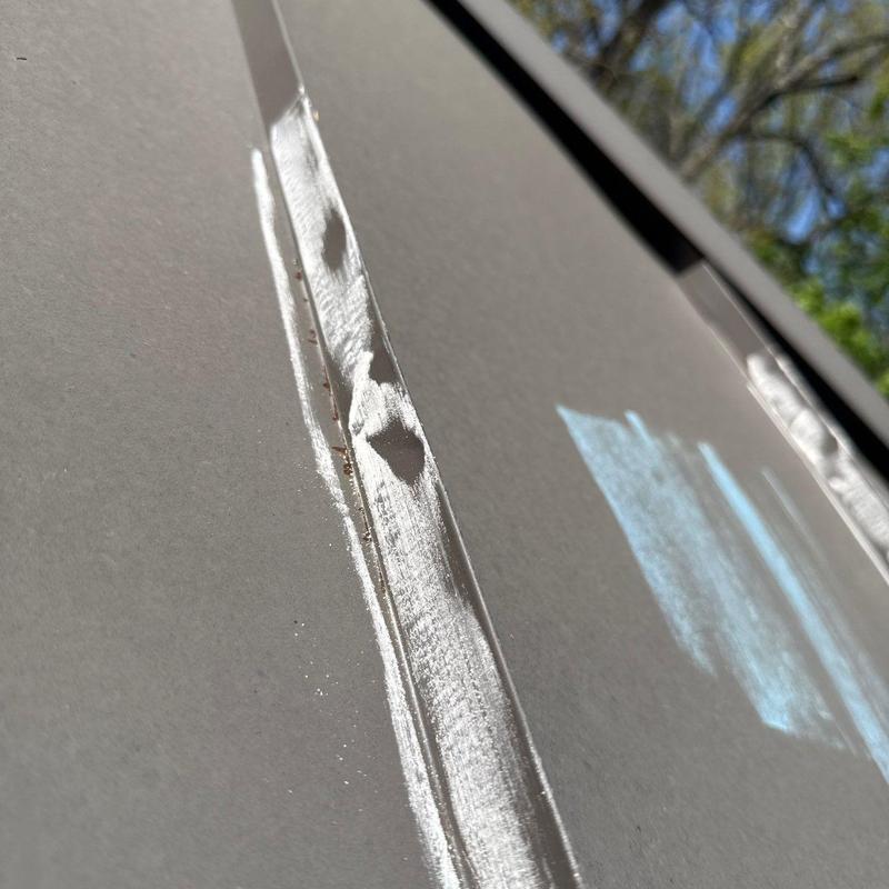 Metal roof panel with hail dents and white marking