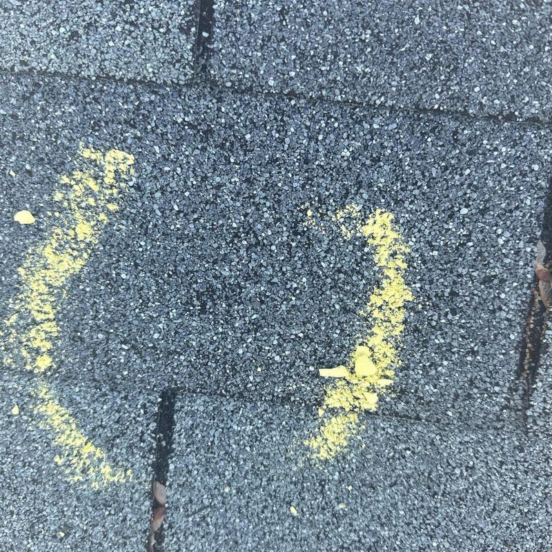 Asphalt shingle hail damage marked with yellow spray paint