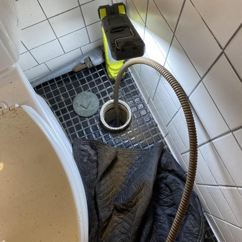 Sewer cleanout with snake clearing blockage in bathroom
