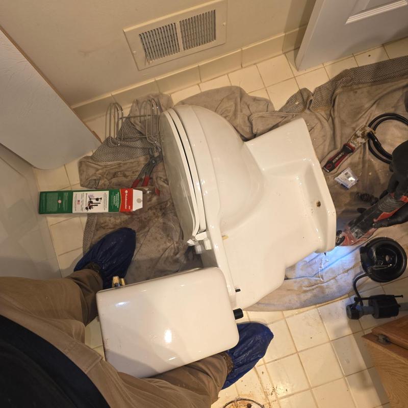 Toilet removed on tile floor with plumbing tools