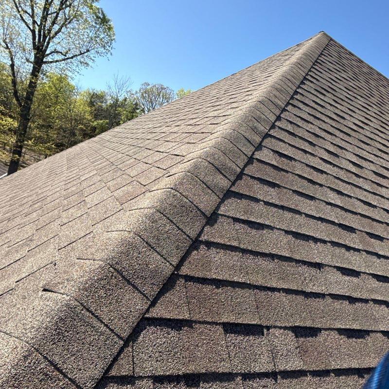 Asphalt shingle roof with ridge cap under clear sky