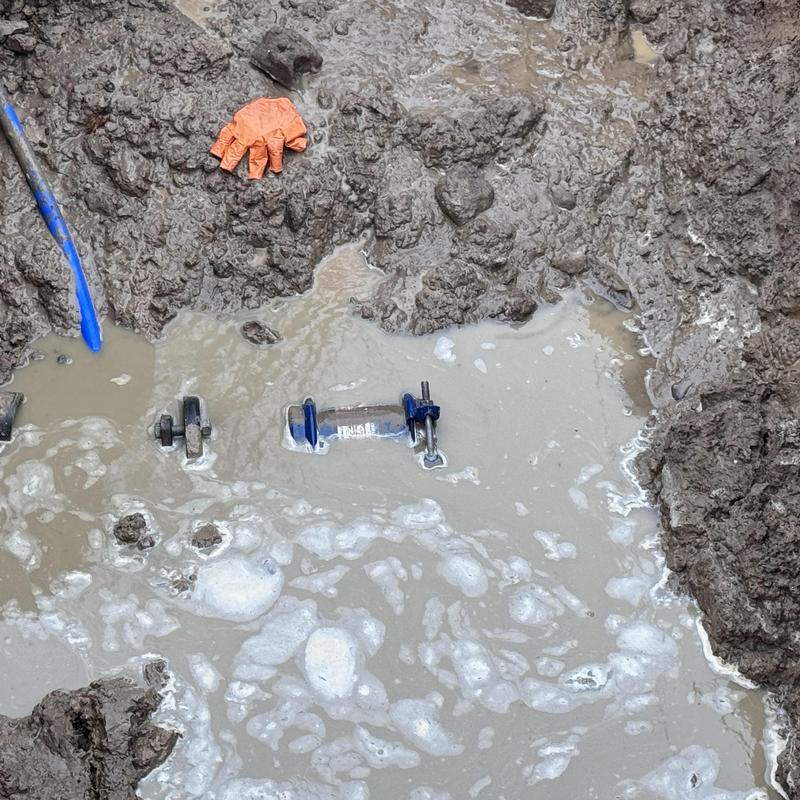 Cast iron water line with repair clamp in muddy hole