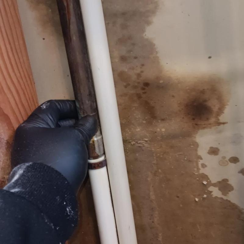 Copper pipe inspection near water damage spot