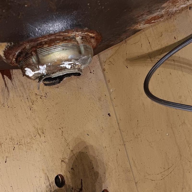 Rusty sink basket strainer under cabinet with hose