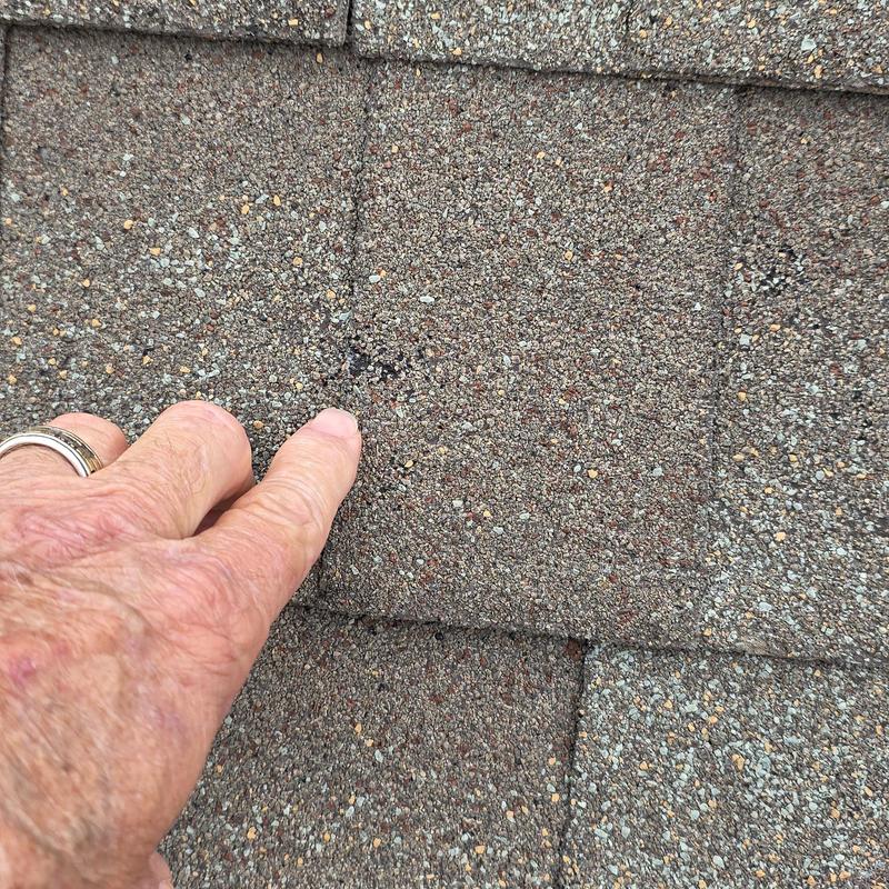 Roof shingles with hail and wind damage mark