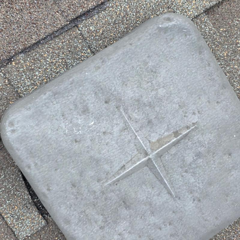 Roof vent cover with hail impact damage on shingles