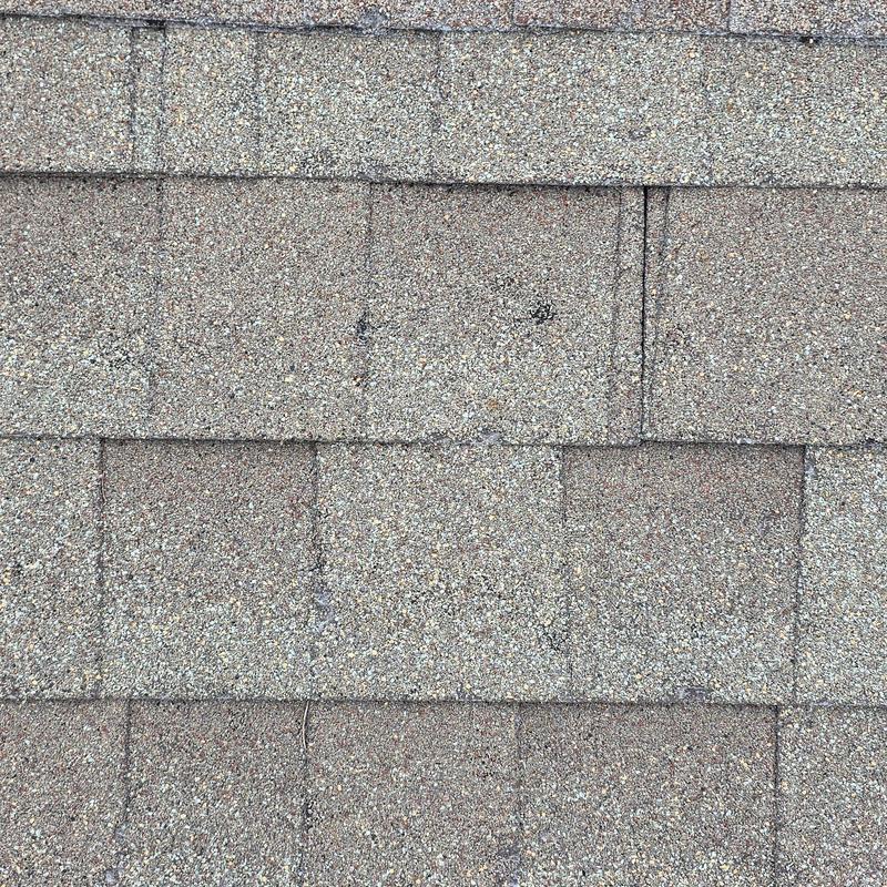 Asphalt roof shingles with black hail impact marks