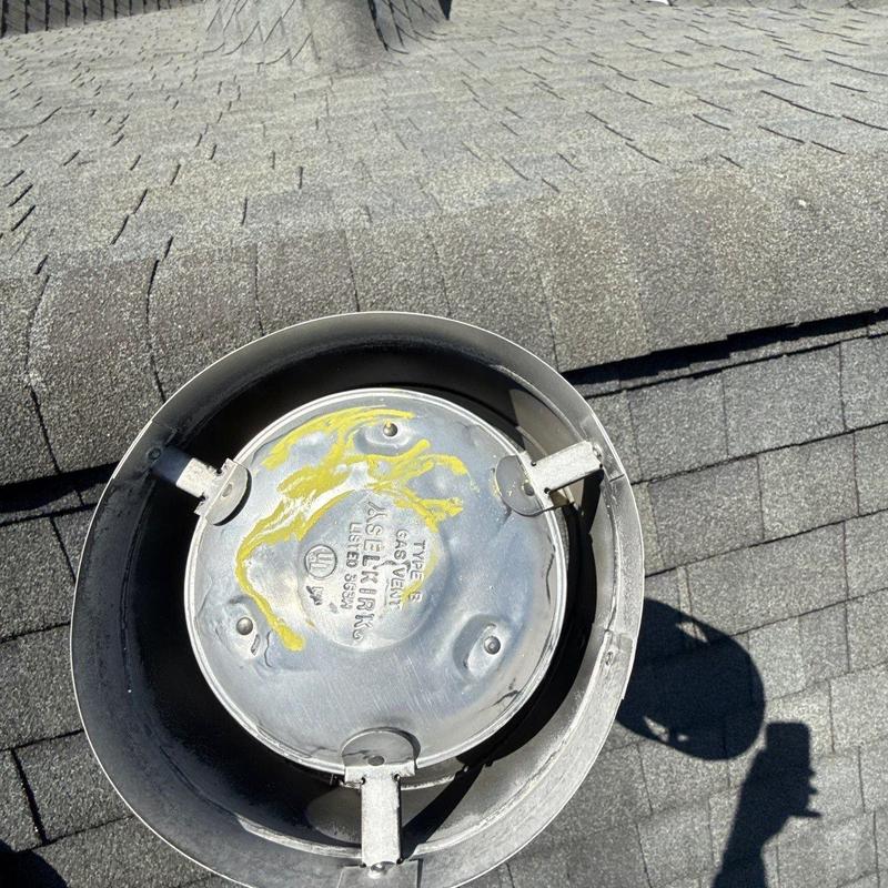 Gas vent cap on shingled roof with hail damage