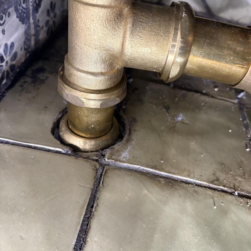 Tub waste and overflow pipe fitting on tiled floor