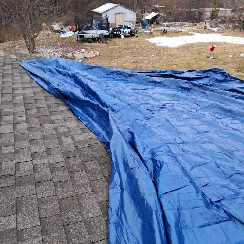 Roof tarp covering damaged shingles for temporary repair Roof tarp covering damaged shingles for temporary repair