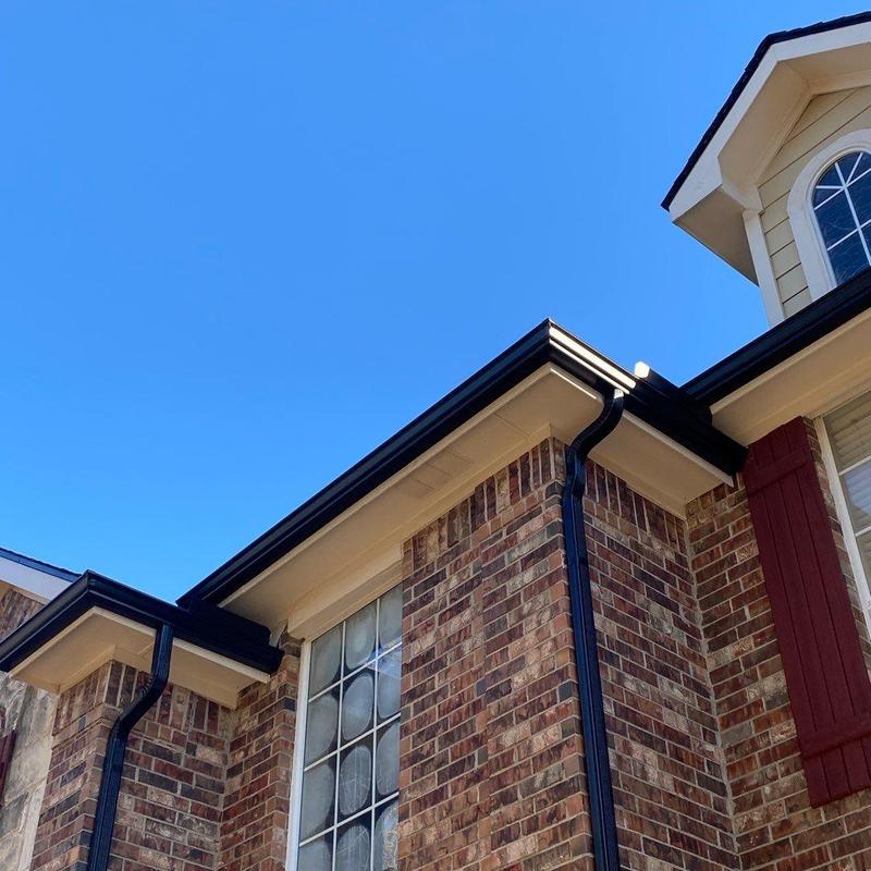 Black seamless gutters on brick home exterior