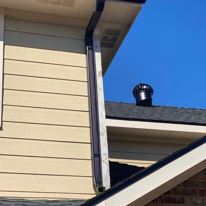 Black seamless gutter and downspout on beige siding