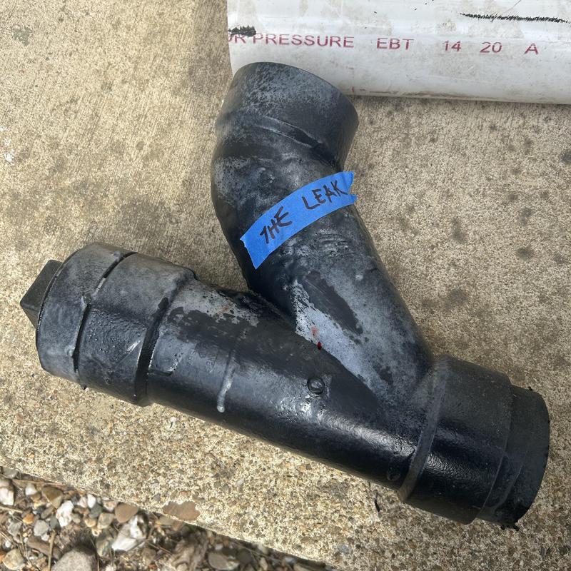 Cast iron sewage pipe section with leak labeled