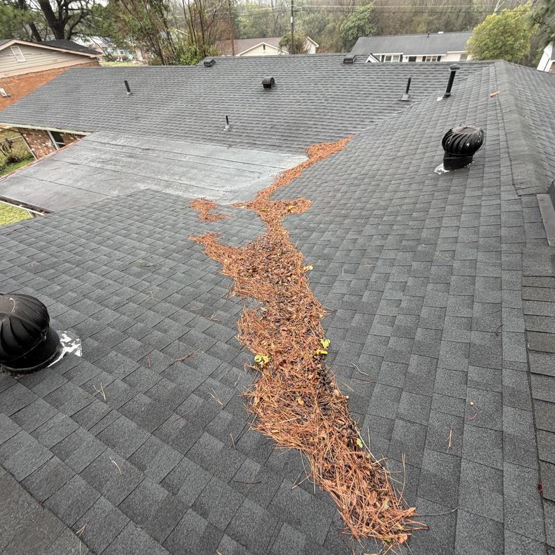 Roof debris buildup along shingled valley during inspection