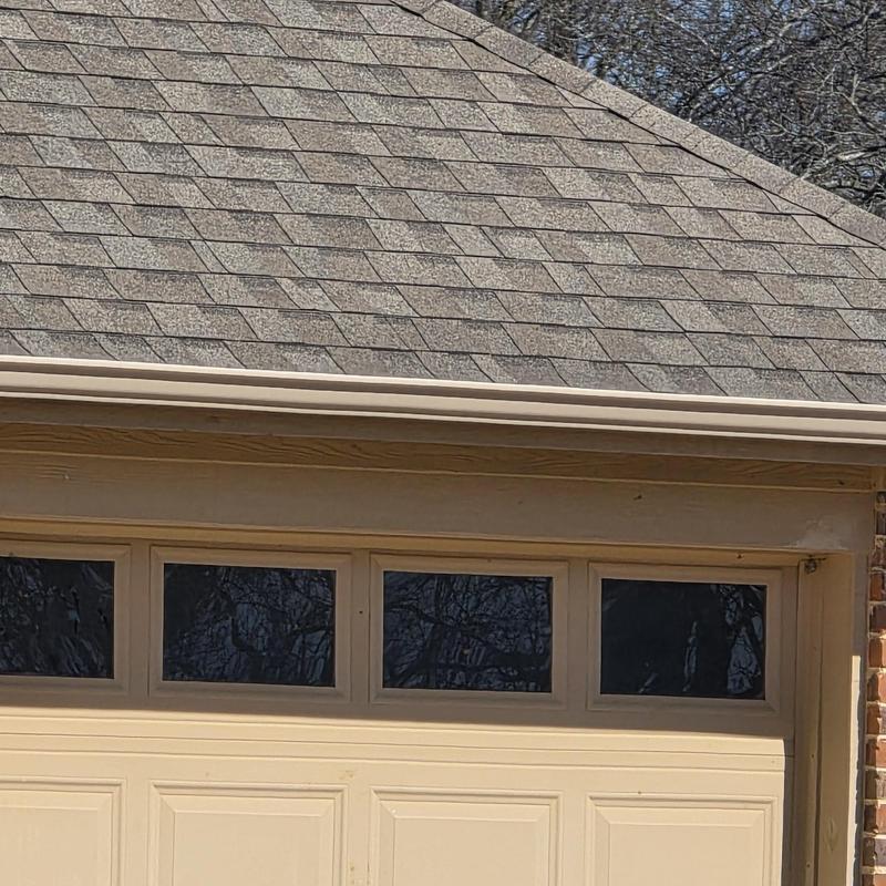 Asphalt shingle roof with hail damage above garage door