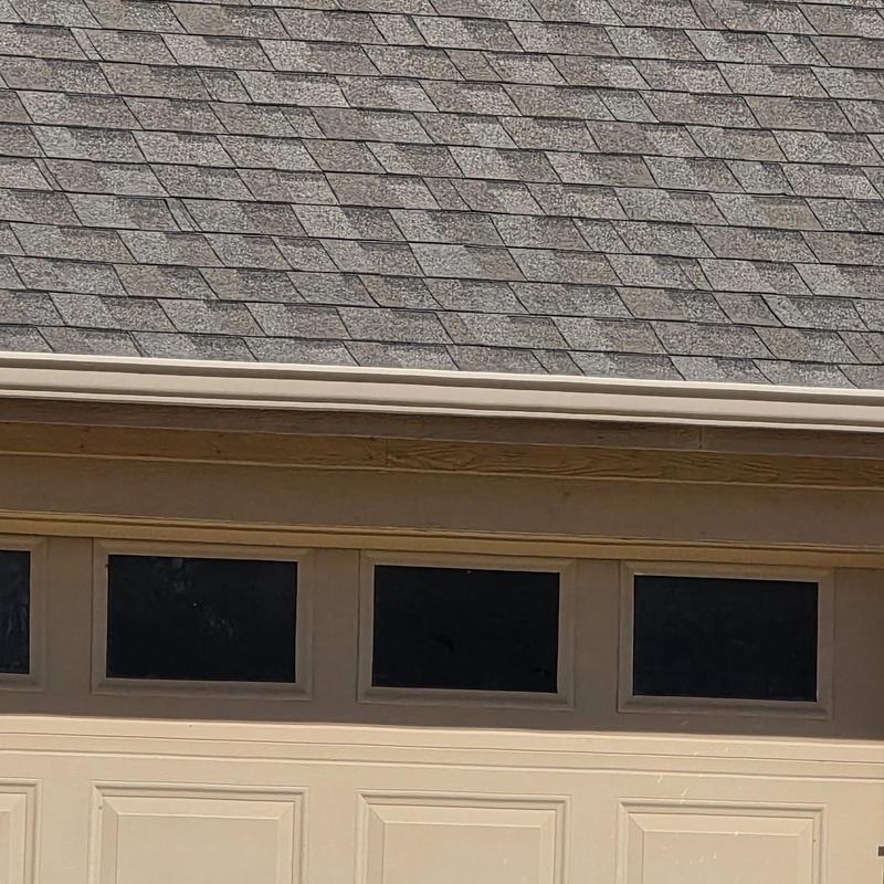 Asphalt shingle roof with hail damage near garage