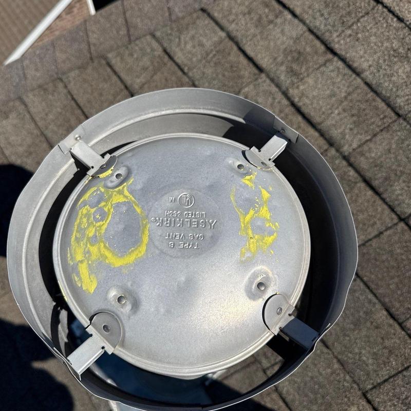 Gas vent cap on shingle roof with hail damage marks